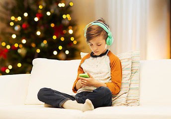 Image showing boy with smartphone and headphones on christmas