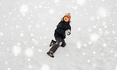 Image showing happy little boy playing with snow in winter