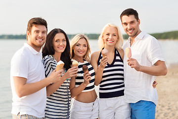 Image showing happy friends eating ice cream on beach