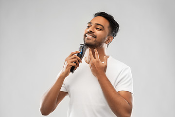 Image showing smiling indian man shaving beard with trimmer