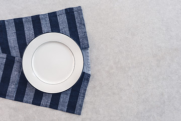 Image showing White plate and striped tablecloth