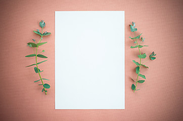 Image showing Blank paper and eucalyptus on rosewood colored canvas