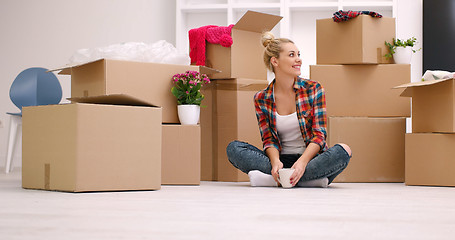 Image showing woman with many cardboard boxes sitting on floor