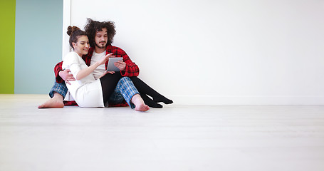 Image showing Young Couple using digital tablet on the floor