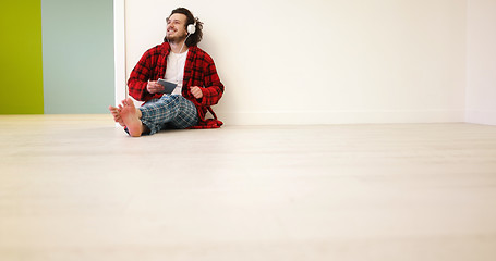 Image showing young man listenig music on tablet at home