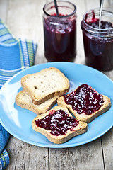 Image showing Fresh cereal bread slices on blue ceramic plate, homemade cherry