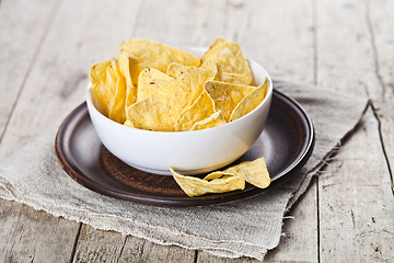 Image showing Mexican nachos chips in white bowl on brown ceramic plate on lin