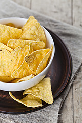 Image showing Mexican nachos chips in white bowl on brown ceramic plate closeu