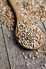 Image showing Organic green dry buckwheat seads in wooden spoon closeup on rus