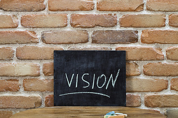 Image showing Chalk board with the word VISION drown by hand and chalks on woo