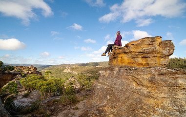 Image showing A bushwalker sits high atop a landscape of pagodas, valleys, gullies and canyons