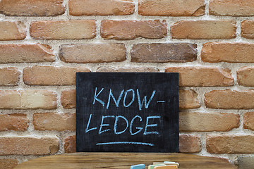 Image showing Chalk board with the word KNOWLEDGE drown by hand and chalks on 