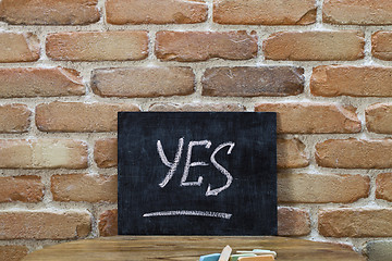 Image showing Chalk board with the word YES drown by hand and chalks on wooden