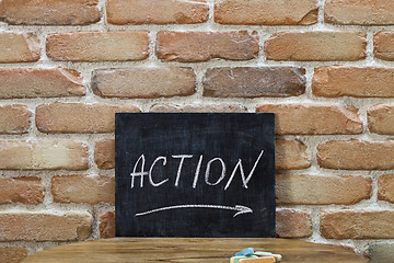 Image showing Chalk board with the word ACTION drown by hand and chalks on woo