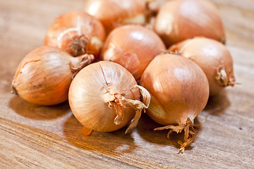 Image showing Fresh organic onions heap closeup on rustic wooden table.