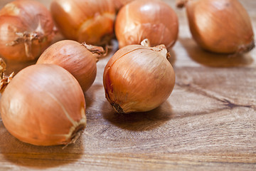 Image showing Fresh organic onions heap closeup on rustic wooden background.