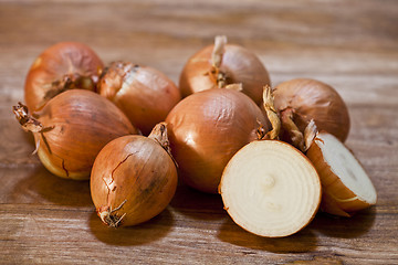 Image showing Organic fresh onions heap closeup on rustic wooden table.