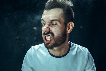 Image showing Young handsome man with beard sneezing, studio portrait