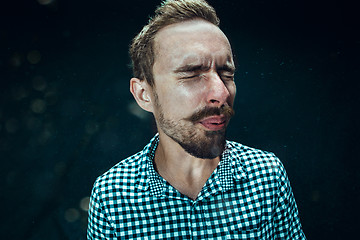 Image showing Young handsome man with beard sneezing, studio portrait