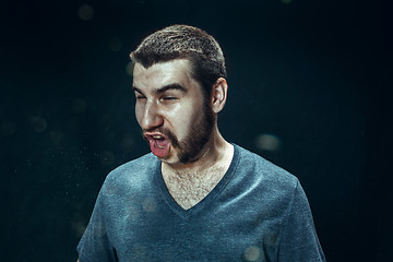 Image showing Young handsome man with beard sneezing, studio portrait