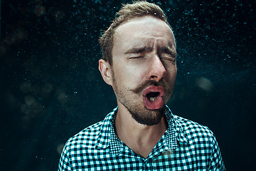 Image showing Young handsome man with beard sneezing, studio portrait