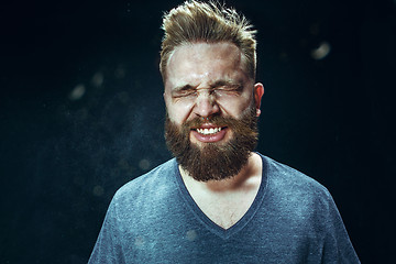 Image showing Young handsome man with beard sneezing, studio portrait