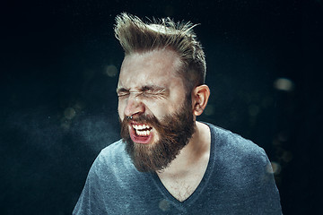 Image showing Young handsome man with beard sneezing, studio portrait