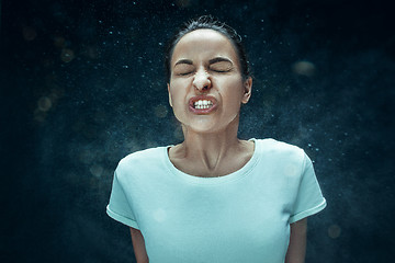 Image showing Young woman sneezing, studio portrait