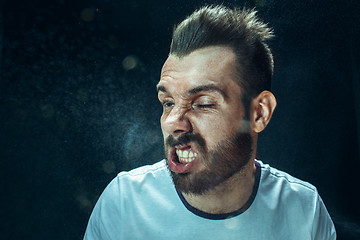 Image showing Young handsome man with beard sneezing, studio portrait