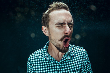 Image showing Young handsome man with beard sneezing, studio portrait