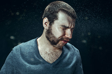 Image showing Young handsome man with beard sneezing, studio portrait