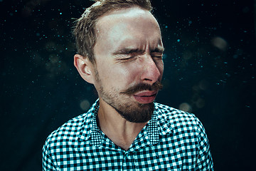 Image showing Young handsome man with beard sneezing, studio portrait