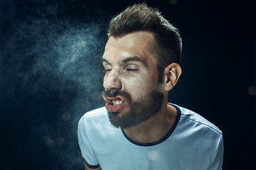 Image showing Young handsome man with beard sneezing, studio portrait