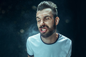 Image showing Young handsome man with beard sneezing, studio portrait