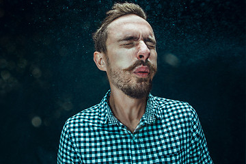 Image showing Young handsome man with beard sneezing, studio portrait