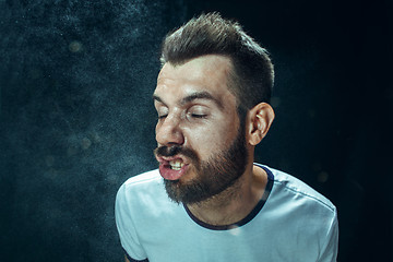 Image showing Young handsome man with beard sneezing, studio portrait