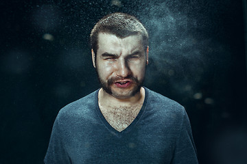 Image showing Young handsome man with beard sneezing, studio portrait