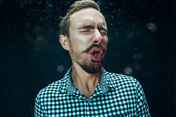 Image showing Young handsome man with beard sneezing, studio portrait