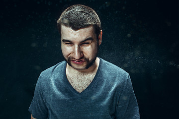 Image showing Young handsome man with beard sneezing, studio portrait