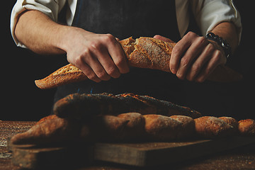 Image showing Baker\'s hands break the baguette