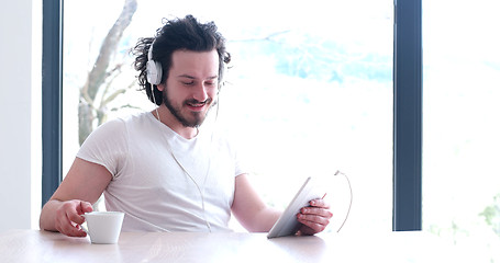 Image showing young man listenig music on tablet at home