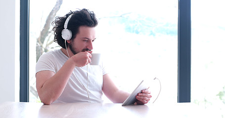 Image showing young man listenig music on tablet at home