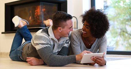 Image showing multiethnic couple using tablet computer on the floor