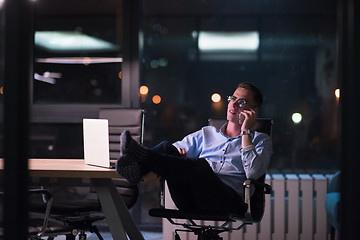 Image showing businessman using mobile phone in dark office