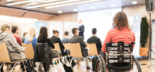 Image showing Rear view of unrecognizable woman on a wheelchair participating at business conference talk.