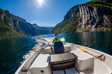 Image showing Woman driving a motor boat Seven Sisters waterfall on the backgr