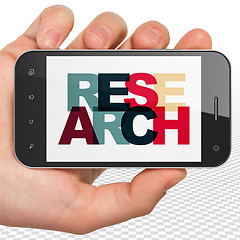 Image showing Marketing concept: Hand Holding Smartphone with Research on  display