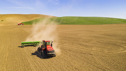 Image showing Red Tractor tows the Plow in the agricultural farm field