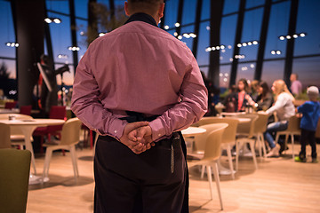 Image showing waiter standing with hands behind his back