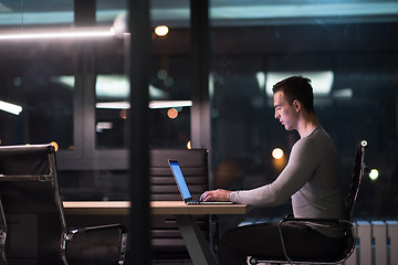 Image showing man working on laptop in dark office